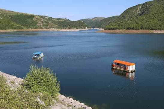 Turistički brodovi na mirnoj vodi Uvačkog jezera između zelenih padina